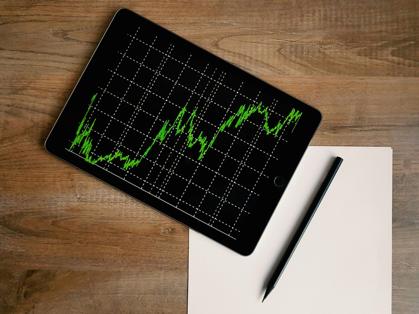 pexels-photo-187041-187041 Flatlay of an iPad displaying stock market graph on a wooden desk with a pencil and paper.