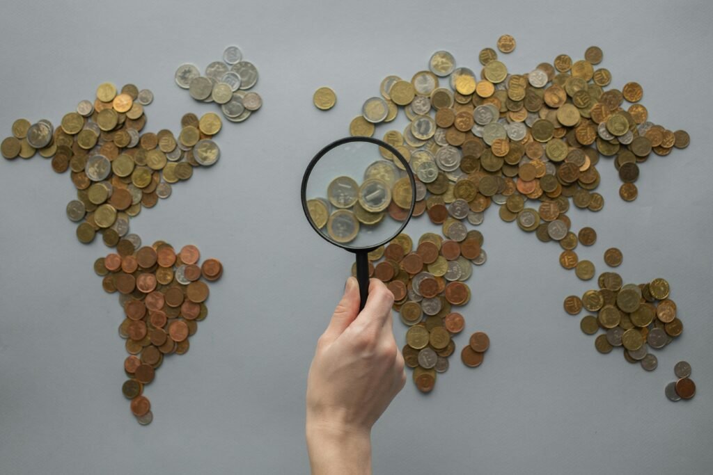 pexels-photo-7412089-7412089 A creative world map composed of coins with a magnifying glass highlighting Europe.