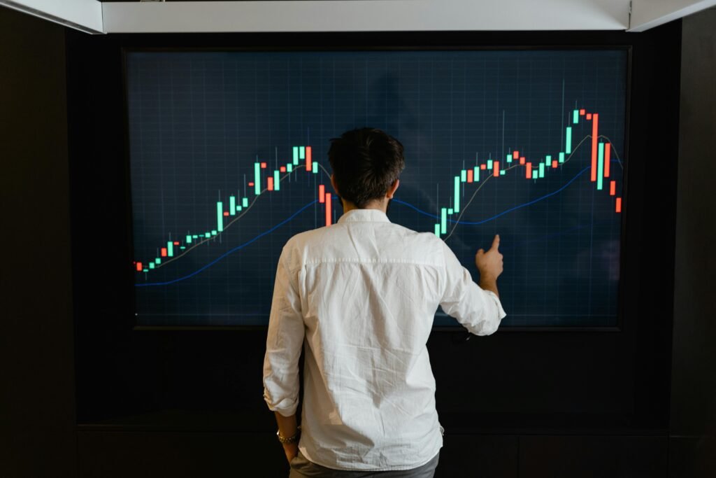 pexels-photo-7567591-7567591 Adult male reviewing stock market data on a large display screen indoors.