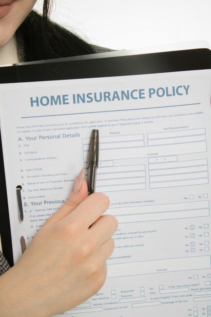 pexels-photo-7736031-7736031 Close-up of a hand holding a home insurance policy document with a pen.