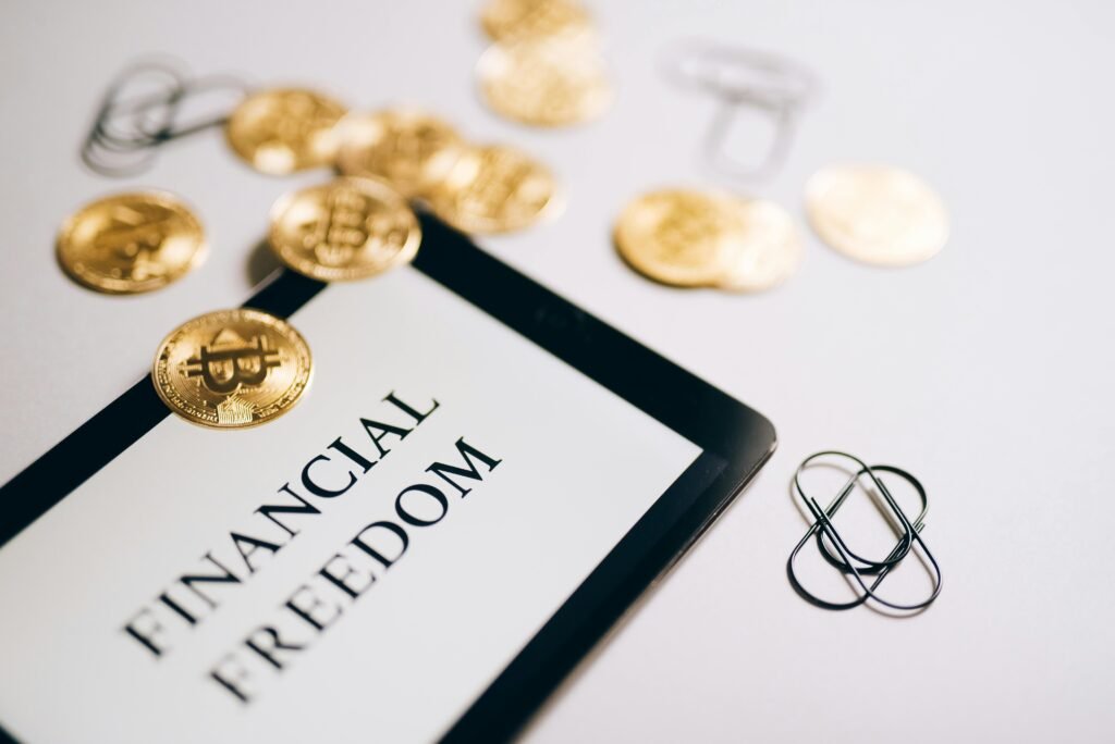 pexels-photo-8919509-8919509 Close-up of Bitcoin coins and an iPad displaying 'Financial Freedom,' symbolizing modern digital savings. investing without a high salary