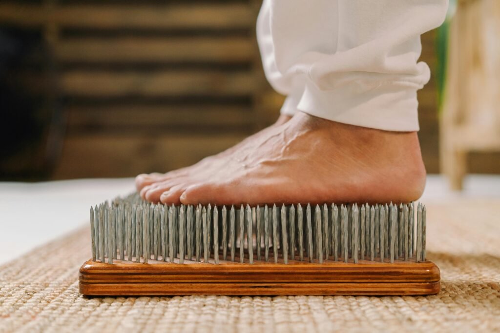 A close-up shot of a barefoot person standing on a nail board, used in meditation and pain tolerance practices.